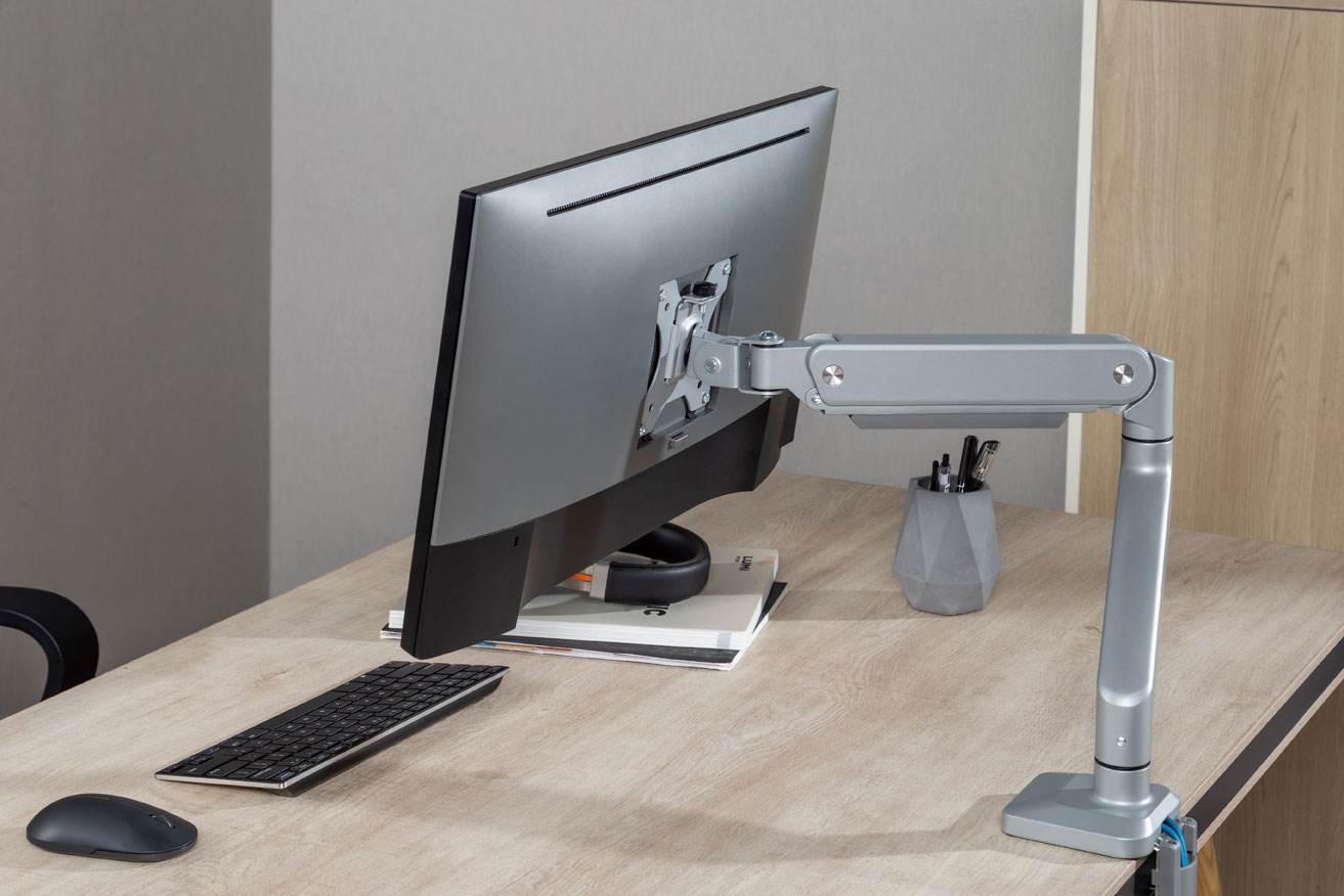 jps31 monitor arm on a light wood table with books and keyboard